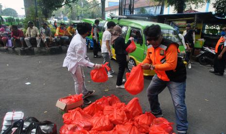 Relawan bersama petugas Dishub Kota Bogor membagikan paket sembako untuk supir angkot di jalan Juanda, Kota Bogor, Jawa Barat, Senin (13/4/2020). Pembagian 300 paket sembako untuk supir angkot tersebut untuk membantu meringankan beban ekonomi para supir angkot yang penghasilannya berkurang karena sepinya penumpang akibat wabah pandemi virus Corona (COVID-19).