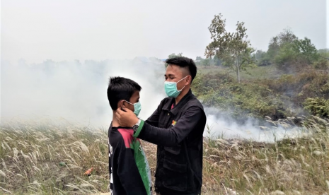 Relawan BMH memakaikan masker kepada seorang bocah korban asap di Palangkaraya.