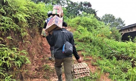 Relawan BMH menyusuri jalanan licin dengan memanggul bantuan dan menenteng telur untuk korban musibah tanah longsor di Desa Sejati, Mamuju.