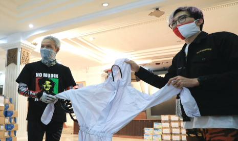 Relawan BNPB, dr Tirta Mandira Hudhi (kanan) bersama Gubernur Jawa Tengah, Ganjar Pranowo menunjukkan baju hazmat bantuan Junior Doctors Network Indonesia yang disalurkan untuk mendukung penanganan Covid-19 di Jawa Tengah, Jumat (17/4).