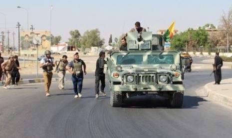 Relawan dan pasukan Peshmerga Kurdi membawa senjata di utara Kirkuk, Irak, Senin (16/10).