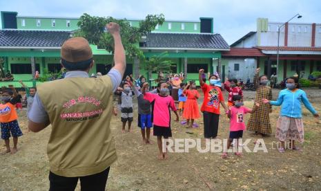 Relawan dari Gerakan Pemuda Ansor mengajak anak-anak bermain dan bernyanyi di posko pengungsian korban banjir Desa Karangrowo, Undaan, Kudus, Jawa Tengah, Rabu (10/2/2021). Kegiatan tersebut dilakukan untuk pemulihan trauma anak-anak korban bencana banjir. 