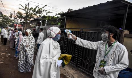 Relawan Dewan Kemakmuran Masjid Al Jihad memeriksa suhu tubuh warga sebelum mengikuti sholat ied.