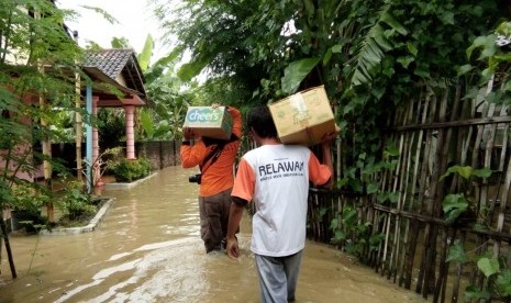 Relawan Laznas BMH memanggul bantuan logistik untuk korban terdampak banjir di Madiun.