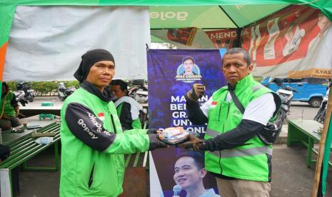 Relawan Mas Gibran memberikan bantuan kepada pengemudi ojek online.