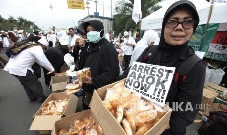 Relawan membagikan makanan gratis kepada para peserta sebagai bentum dukungan terhadap aksi Super Damai 212 di kawasan silang Monas, Jakarta,Jumat (2/12). 