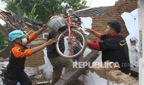 Relawan membantu warga menyelamatkan barang di sebuah rumah yang hancur akibat gempa di Majangtengah, Malang, Jawa Timur, Ahad (11/4/2021). Kementerian Sosial menerjunkan 700 personel Tagana di sejumlah lokasi terdampak bencana gempa Malang untuk membantu mengevakuasi korban, membangun tempat pengungsian, mendirikan dapur umum dan menyelenggarakan layanan dukungan psikososial.