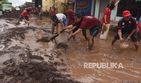 Relawan membersihkan endapan lumpur di lokasi dampak banjir / Ilustrasi 