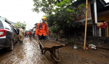 Relawan membersihkan lumpur yang terbawa banjir di Perumahan Bumi Mangli, Kaliwates, Jember, Jawa Timur.