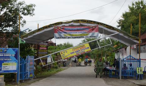 Relawan menjaga gerbang berportal di jalan masuk wilayah desa saat Pemberlakuan Pembatasan Kegiatan Masyarakat (PPKM) Mikro, di Desa Ngale, Pilangkenceng, Kabupaten Madiun, Jawa Timur, Sabtu (20/2/2021). Desa Ngale mewakili wilayah Korem 081/Dhirotsaha Jaya Madiun dalam lomba Program PPKM Mikro tingkat Kodam V/Brawijaya yang diikuti seluruh Korem di Jawa Timur guna peningkatan pencegahan COVID-19.