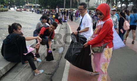  Relawan peduli Jakarta Bersih membersihan sampah yang berserakan di kawasan Hari Bebas Kendaraan Bermotor (HBKB) di Bundaran HI, Jakarta, Ahad (20/12). (Republika/Yasin Habibi)