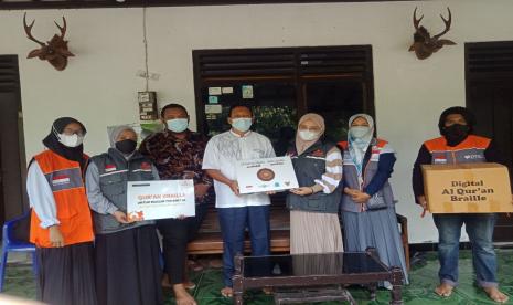 Relawan Rumah Zakat menyusuri gang kecil di Desa Jogotirto, Berbah, Sleman dengan membawa Alquran Braille Digital.