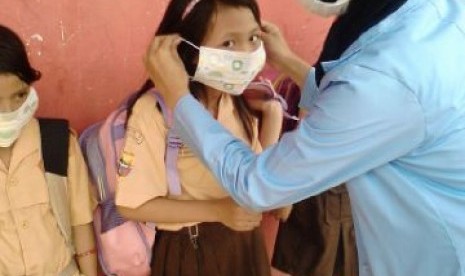 Relawan SIKAP memasangkan masker pada siswa SD yang Palembang, Sabtu (17/10). 