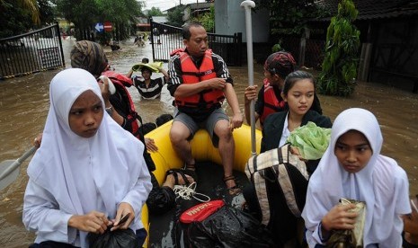 Relawan Tagana menggunakan perahu karet mengantar warga dan pelajar menuju rumah mereka yang terendam banjir di Perumahan Bukit Cengkeh II, Cimanggis, Depok, Jawa Barat, Jumat (12/2).(Antara/Indrianto Eko Suwarso)