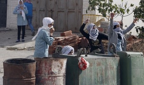 Remaja putri Palestina melemparkan batu ke aparat Israel di Kota Hebron, Rabu (13/10)