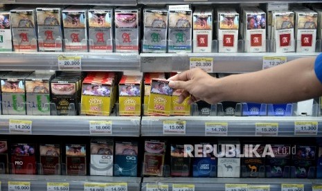 Petugas toko mengambil rokok untuk konsumen di salah satu ritel, Jakarta.