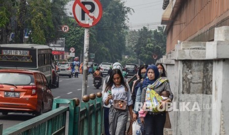 Pejalan kaki melintasi trotoar di daerah Stasiun Cikini, Jakarta Pusat. Pejalan kaki menjadi kelompok paling rentan yang terdampak polusi udara.