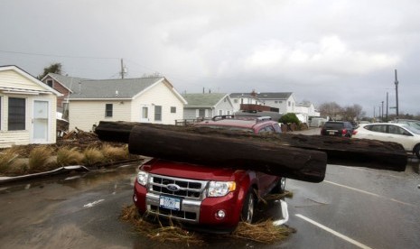 Reruntuhan sebatang pohon besar menimpa sebuah mobil di Breezy Point New York, Selasa (30/10). (Frank Franklin II/AP)