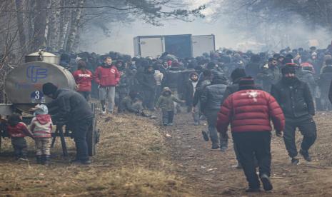 Ribuan imigran yang terjebak di perbatasan Belarusia berebut bantuan kemanusiaan di Grodno, Belarusia, 11 November 2021. Menurut militer Inggris ada kemungkinan perang dengan Rusia terkait krisis pengungsi.