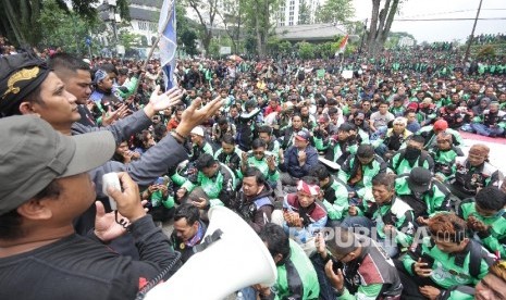 Ribuan pengemudi trasportasi berbasisi aplikasi online berdoa saat menggelar aksi di depan Gedung Sate, Kota Bandung, Senin (16/10).