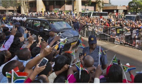  Ribuan warga mengibarkan bendera saat menyaksikan mobil yang membawa jenazah mantan Presiden Nelson Mandela di Pretoria, Afrika Selatan, Kamis (12/12).   (AP/Bend Curtis)