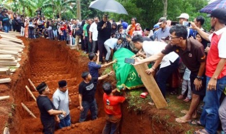 Ribuan warga menyaksikan prosesi pemakaman korban kecelakaan bus di tanjakan Emen, Subang, di Tempat Pemakaman Umum (TPU) Legoso Ciputat, Tangerang Selatan, Banten, Ahad (11/2). Sebanyak 26 orang korban tewas kecelakaan bus pariwisata di tanjakan Emen, Subang yang kesemuanya warga Legoso Ciputat, dimakamkan secara massal. 