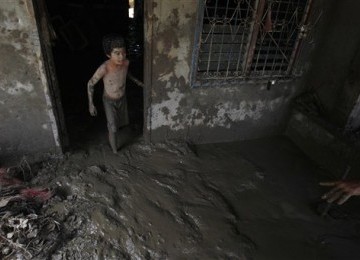 Richard Racadio (9), warga Filipina korban banjir membersihkan rumahnya di Kota Iligan yang terendam lumpur, Rabu (21/12).