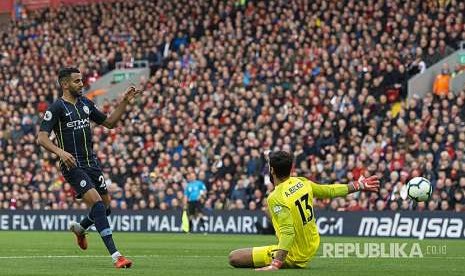 Riyad Mahrez (kiri) berhadapan dengan kiper Liverpool Alisson Becker (kanan) pada pertandingan Liga Primer Inggris antara Liverpool melawan Manchester City di Stadion Anfield, Ahad (7/10) waktu setempat.