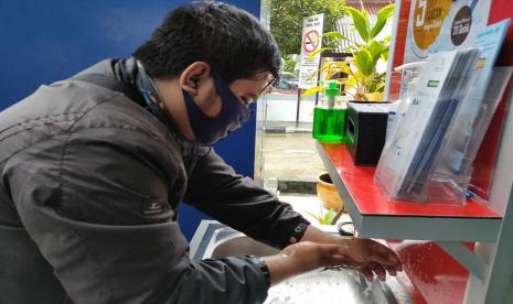 Rizal Novianto (30) terlihat sedang mencuci tangan di wastafel yang telah disediakan sebelum masuk ke dalam kantor BPJS Kesehatan Cabang Pontianak.