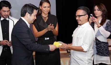 Robert Ronny (kiri) saat memberi potongan tumpeng ke Ody C Harahap saat syukuran film 