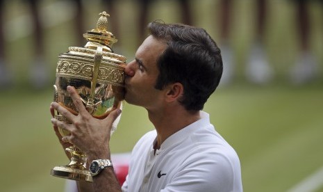 Roger Federer mencium trofi Wimbledon setelah mengalahkan Marin Cilic pada partai final, Ahad (16/7).