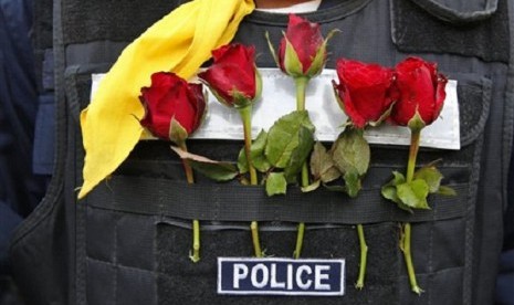 Roses offered by anti-government protesters decorate a Thai policeman's bulletproof vest outside city police headquarters, in Bangkok, Thailand Tuesday, Dec. 3, 2013. 