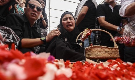 Almyanda Safira (tengah) ibunda dari korban tewas dalam kasus pembunuhan Pulomas Dianita Gemma Dzalfayla dan Diona Arika Andra Putri menaburkan bunga di makam kedua anaknya di TPU Tanah Kusir, Jakarta, Rabu (28/12).