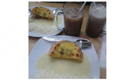 Roti comel disajikan dengan susu kental manis dan keju parut di sisinya.