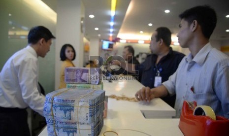 Teller melakukan transaksi dengan nasabah di Banking Hall Bank Mandiri, Jakarta. 