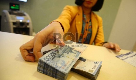 Rupiah Semakin Melemah: Teller melakukan transaksi dengan nasabah di Banking Hall Bank Mandiri, Jakarta, Rabu (11/3).