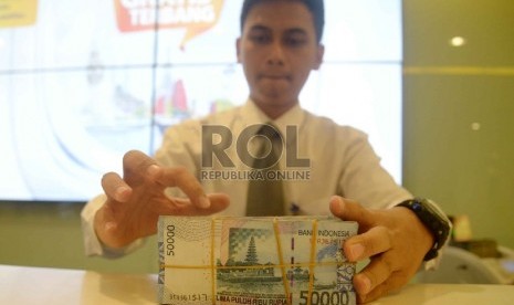 Rupiah Semakin Melemah: Teller melakukan transaksi dengan nasabah di Banking Hall Bank Mandiri, Jakarta, Rabu (11/3).