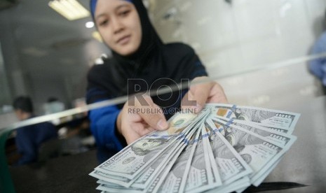 Rupiah Terus Merosot: Petugas menghitung uang rupiah dan dolar di salah satu penukaran uang di Jakarta, Kamis (5/3).