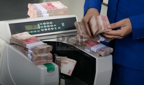 Rupiah Terus Merosot: Petugas menghitung uang rupiah dan dolar di salah satu penukaran uang di Jakarta, Kamis (5/3).