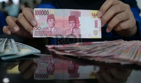 Rupiah Terus Merosot: Petugas menghitung uang rupiah dan dolar di salah satu penukaran uang di Jakarta, Kamis (5/3).