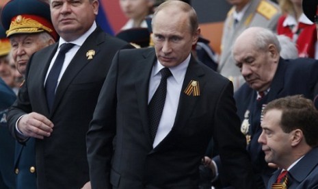 Russia's Defense Minister Anatoly Serdyukov, left, Russian President Vladimir Putin, center, and Prime Minister Dmitry Medvedev, bottom right, watch the Victory Day Parade, in Moscow. (file photo in March 2012)  