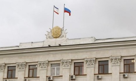 Russia's national flag (R) and Crimea's regional flag are seen on a building of Council of Ministers in Simferopol, March 5, 2014.