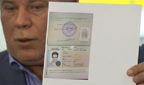 Russian lawyer Anatoly Kucherena shows a temporary document to allow Edward Snowden to cross the border into Russia while speaking to the media after visiting National Security Agency leaker Edward Snowden at Sheremetyevo airport outside Moscow, Russia, on