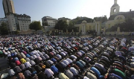 Russian Muslims pray outside a main Mosque which is under a reconstruction, not in the photo, in downtown Moscow on Thursday, Aug. 8, 2013. The Russian Orthodox church is at the background. 