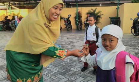 Salah satu guru di PAUD Juara Pekanbaru sedang memberikan permen kepada siswa saat hari pertama sekolah.