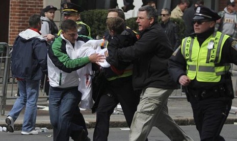 Salah satu korban dalam insiden ledakan bom pada Maraton Boston 2013, Senin (15/4/2013) dievakuasi oleh polisi dan petugas medis.