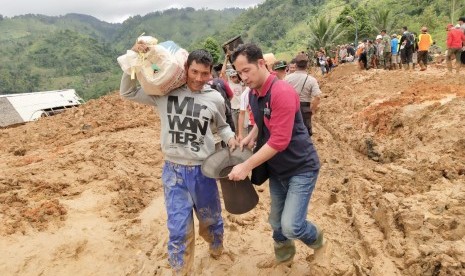 Salah satu relawan AGP (kanan) membantu evakuasi di titik longsor Kecamatan Cisolok, Sukabumi, Rabu (2/1).