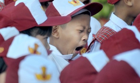 Salah satu siswa menguap di sela upacara bendera pada hari pertama masuk sekolah di Sekolah Dasar Negeri (SDN) 243 Palembang, Sumatera Selatan, Senin (16/7).