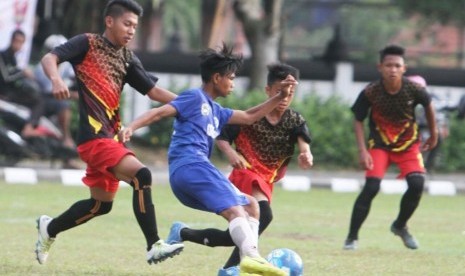 Salah seoarng pemain Jawa Barat (biru) menggiring bola berusaha melewati pemain Kalimantan Barat pada laga Liga Sepak Bola Pelajar (LSP) Piala Menpora 2017 di Magelang, Jumat (8/9).