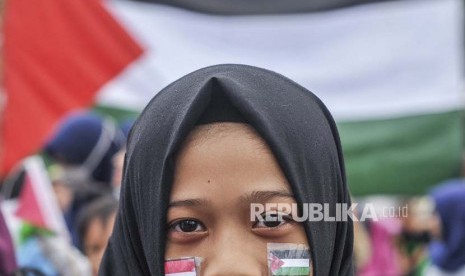 Salah seorang demonstran yang tergabung dalam Voice of Palestine Jawa Barat memasang bendera Indonesia dan Palestina di wajah.